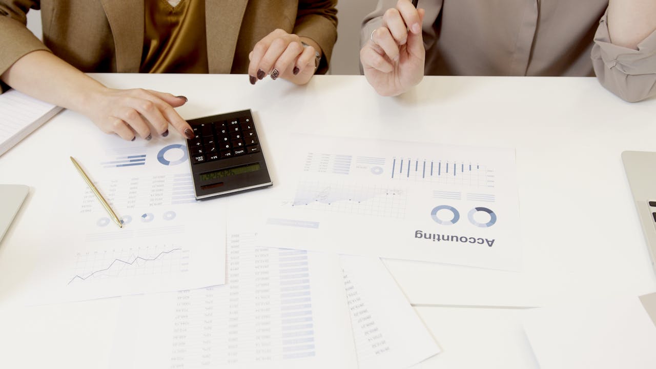 services-img Two professionals analyzing financial documents with a calculator.
