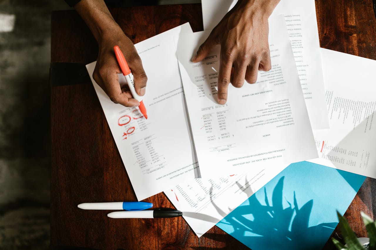 services-02 Overhead view of hands highlighting financial documents on a desk.