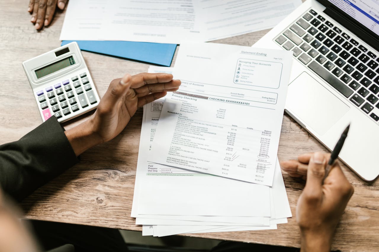 services-01 Hands holding financial documents with calculator and laptop on office desk, business analysis scene.